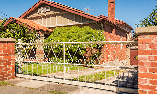 Brunswick woven wire gate has automatic motor behind brick fence driveway